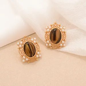 Close-up of vintage tiger eye earrings with pearl floral design on soft cream backdrop