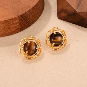Detalle de pendientes vintage de ojo de tigre con marco de metal dorado tejido.