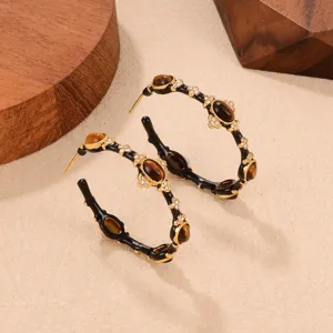 Detail of vintage C-shaped hoop earrings featuring tiger eye stones and crystals.