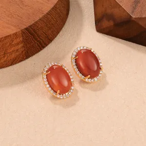 Primer plano de pendientes vintage con piedra roja ovalada y halo de cristal brillante