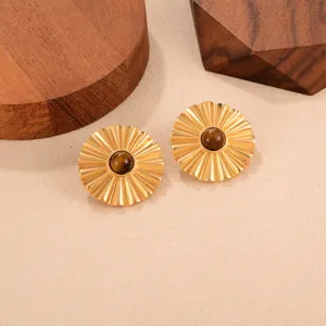 Détail de boucles d'oreilles dorées plissées avec pierre œil de tigre style vintage chic