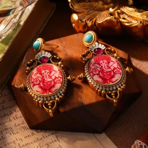 Detail van sierlijke gouden oorbellen in paleisstijl met Ganesha-motief en turquoise.