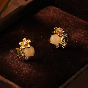 Nahaufnahme von Vintage-Goldohrringen mit gelbem Stein und floralen Zirkonia auf Samt