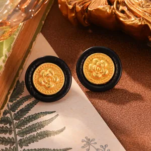 Nahaufnahme von runden Vintage-Ohrsteckern in Schwarz und Gold mit Kamelienmotiv
