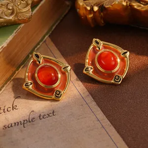 Close-up of vintage gold square stud earrings with red cabochon stone detailing