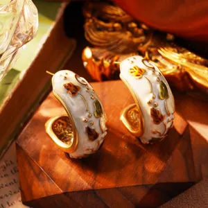 Detaillierte Nahaufnahme französischer Vintage-Creolen aus weißem Email mit Goldblumen