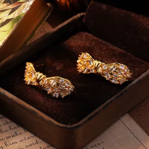 Detailansicht eleganter goldener Schleifenohrringe mit schimmernden Zirkoniasteinen