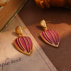Close-up of vintage gold-tone drop earrings with reddish-purple enamel flower relief design
