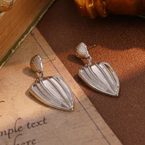 Macro detail of vintage style silver textured grooved drop earrings on a retro paper background