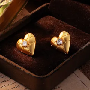 Nahaufnahme von goldfarbenen Herzohrringen mit Kristall in einer Samtbox
