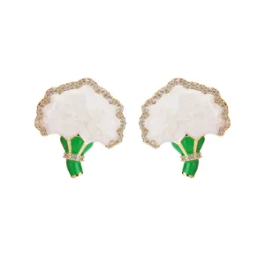Nahaufnahme von eleganten französischen weißen Emaille-Blumenohrsteckern mit grünen Akzenten.