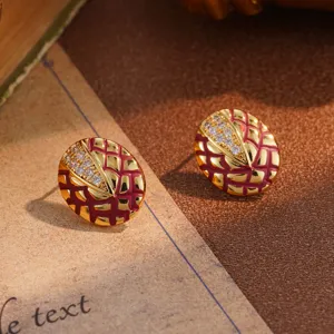 Close-up of vintage gold oval stud earrings with red lattice pattern and rhinestones.