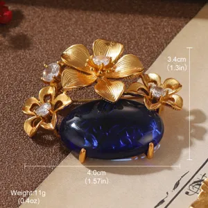 Detail showing vintage gold flower brooch with large oval blue gemstone and rhinestones