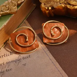 Macro detail view of vintage orange square earrings featuring a golden spiral design