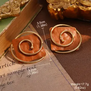 Close-up detail of vintage square gold spiral stud earrings with textured orange base.