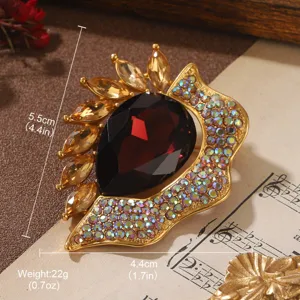 Close-up of vintage gold brooch with large red teardrop gem and colorful rhinestones