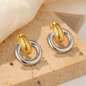 Close-up of gold textured and silver smooth ring earrings on stone