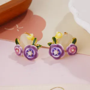 Close-up view of elegant purple enamel flower earrings with dainty pearl centers