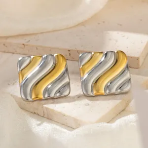 Makroansicht quadratischer, gefalteter Edelstahlohrringe in Gold und Silber.