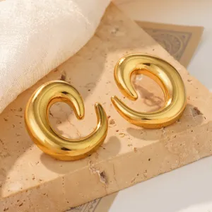 Detailed view of chunky gold-colored spiral conch-shaped stud earrings on stone