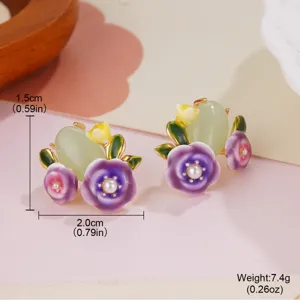 Macro detail of enamel flower earrings featuring pearls and a green heart stone