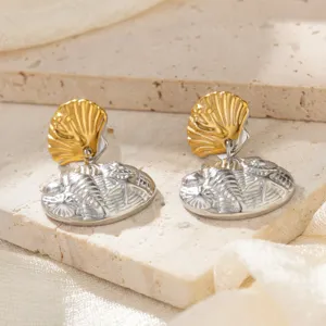 Nahaufnahme goldener und silberner Muschelohrringe aus Edelstahl auf einer Steinunterlage