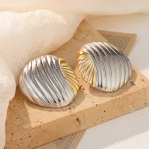Macro detail of two-tone gold and silver stainless steel seashell stud earrings