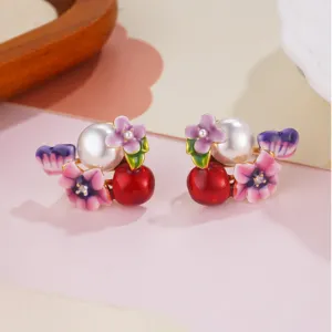 Close-up detail of elegant enamel flower earrings with pearls and red beads