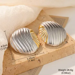 Close-up of oversized stainless steel conch shell earrings with ribbed texture and size