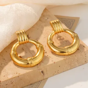 Detailed view of golden stainless steel hoop earrings with ribbed texture on a stone slab