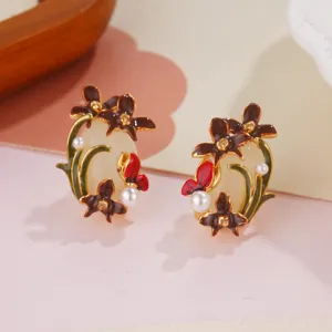 Detailed view of elegant enamel flower and butterfly earrings featuring white pearl accents.