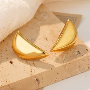 Detailed close-up of gold conch-shaped stainless steel earrings on a stone base