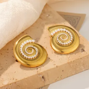 Detailed close-up showing texture of gold spiral conch stud earrings with white pearl inlay