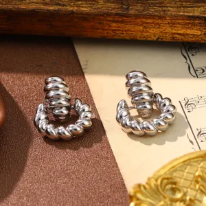 Detailed view of vintage silver-tone ribbed C-shape earrings on musical paper background.
