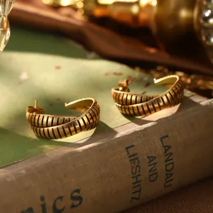 Vue détaillée de boucles d'oreilles vintage en or avec design nervuré sur un livre.