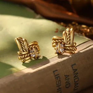 Gros plan de boucles d'oreilles vintage en or avec zircon sur un vieux livre ancien.