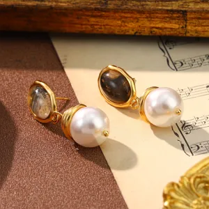 Close-up of vintage gold earrings with dark oval stone and white pearl drop