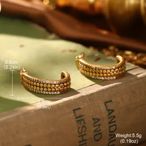 Gros plan sur des créoles dorées vintage avec pierres brillantes et perles texturées