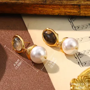 Close-up of vintage pearl drop earrings with dark oval stone in gold frame