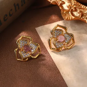 Gros plan de boucles d'oreilles fleurs vintage avec pierre rose et placage d'or