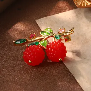 Gros plan détaillé d'une broche framboise rétro avec feuilles dorées et cristaux rouges