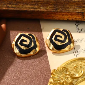 Detail showing a pair of vintage gold earrings with an elegant black enamel spiral rose design