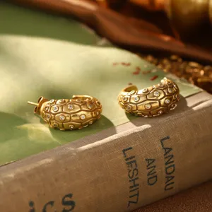 Vue détaillée de boucles d'oreilles dorées vintage avec motif en nid d'abeille et cristaux.