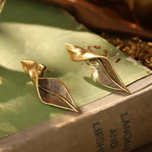 Gros plan détaillé sur des boucles d'oreilles vintage en forme de feuille dorée torsadée