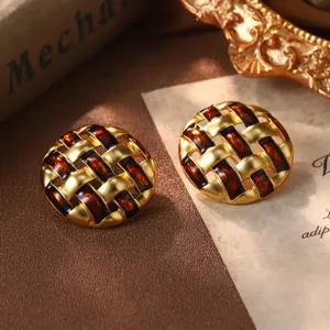 Gros plan détaillé de boucles d'oreilles vintage rondes en émail ambré et design tissé doré