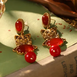 Détail des boucles d'oreilles chat style cour vintage avec pierres rouges et fini doré