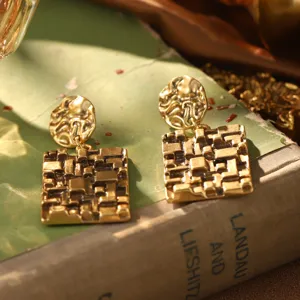 Détail rapproché de boucles d'oreilles vintage en métal doré à texture géométrique