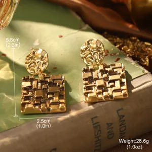 Détail macro de boucles d'oreilles vintage de style cour dorée à goutte carrée texturée