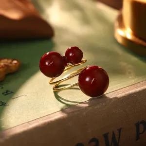Nahaufnahme eines goldenen Rings im Vintage-Stil mit drei tiefroten Perlen auf einem Buch
