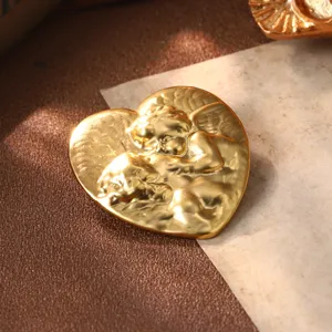 Gros plan d'une boucle d'oreille cœur vintage en or avec motif d'ange gaufré